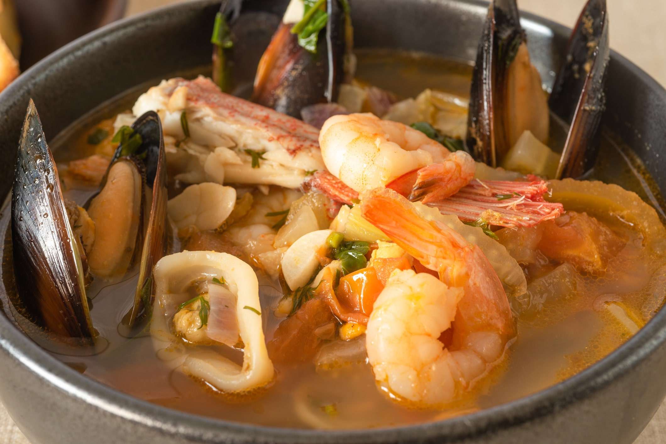 A bowl of San Francisco cioppino with shrimp, mussels, crab and fish in a seasoned broth