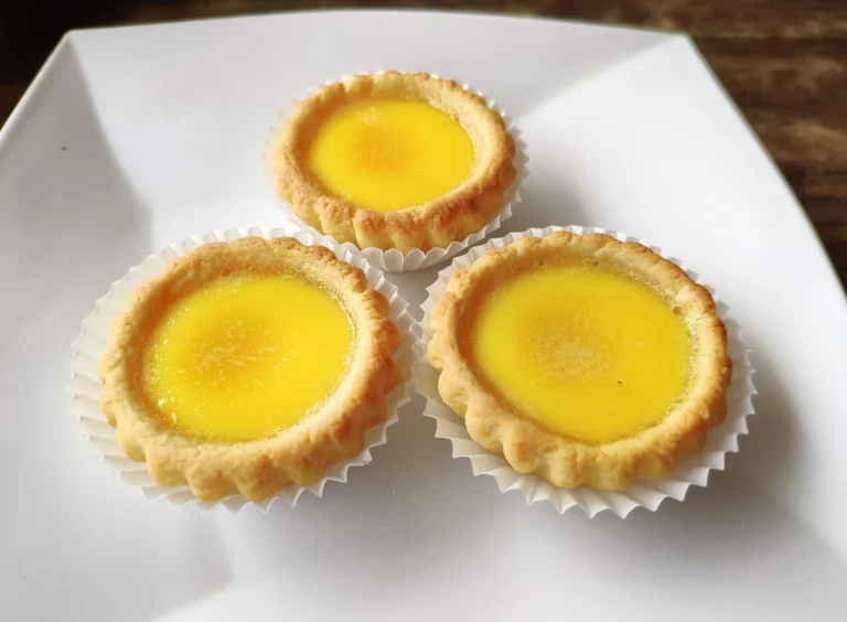 Egg Tarts in paper cups on a white plate are a what to eat in san francisco treat