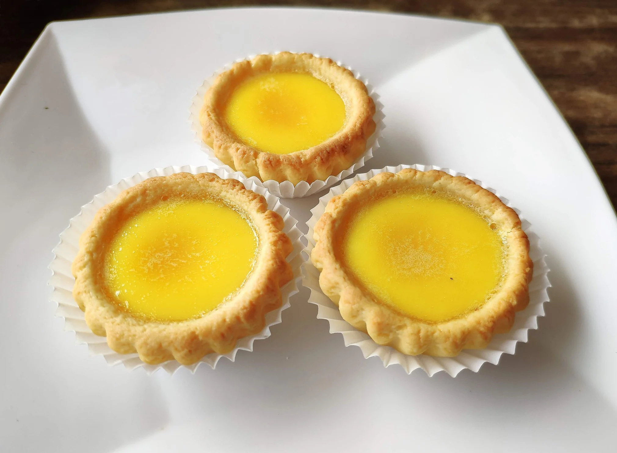 Egg Tarts in paper cups on a white plate are a what to eat in san francisco treat