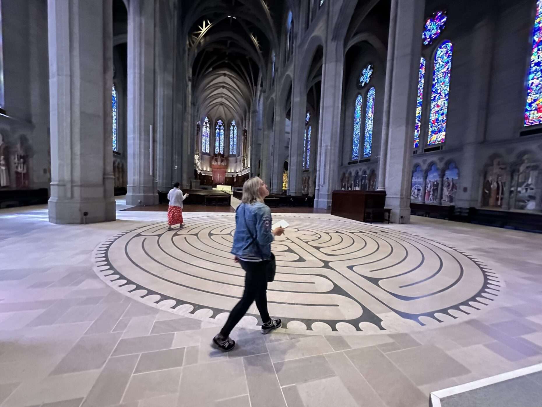 Woman walking the labyrinth inside Grace Caathedral looking at stained glass windows