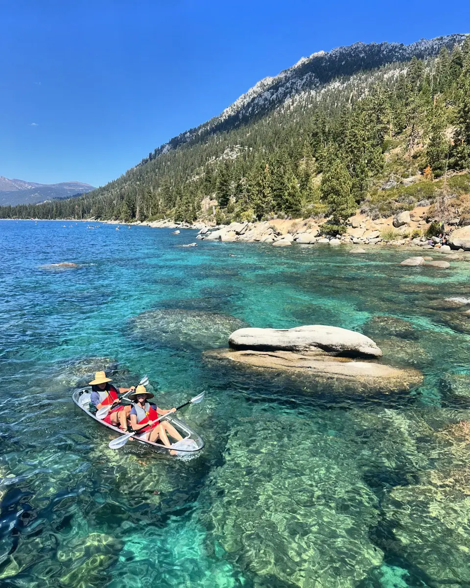 a couple in a kayak over clear turquoise water in lake tahoe