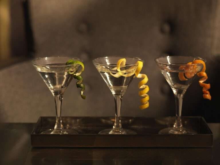 Three martini glasses with citrus twists on a serving tray