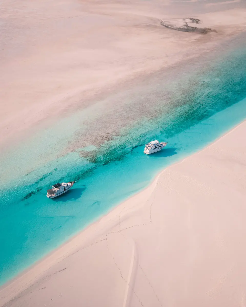 aerial view of turquoise water with boats and sandy beach
