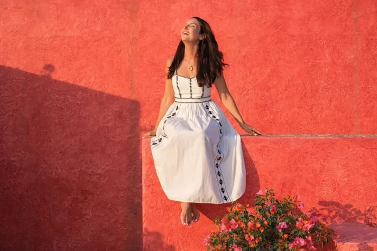 local careyes resident kim kessler in a white dress sitting by a red building