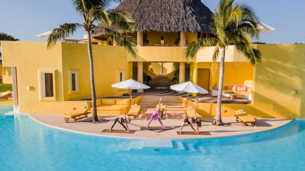 kim kessler teaching a yoga class at a yellow mexican villa by the pool
