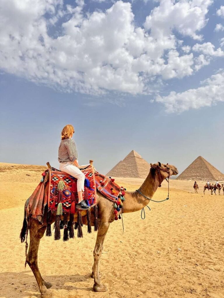 Sitting on a camel in Egypt looking at the pyramids in the distance