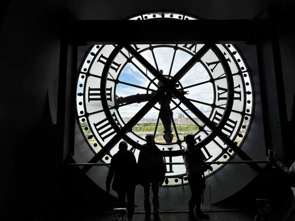 Clock of the musee d'orsay in paris with silhouette of people looking out