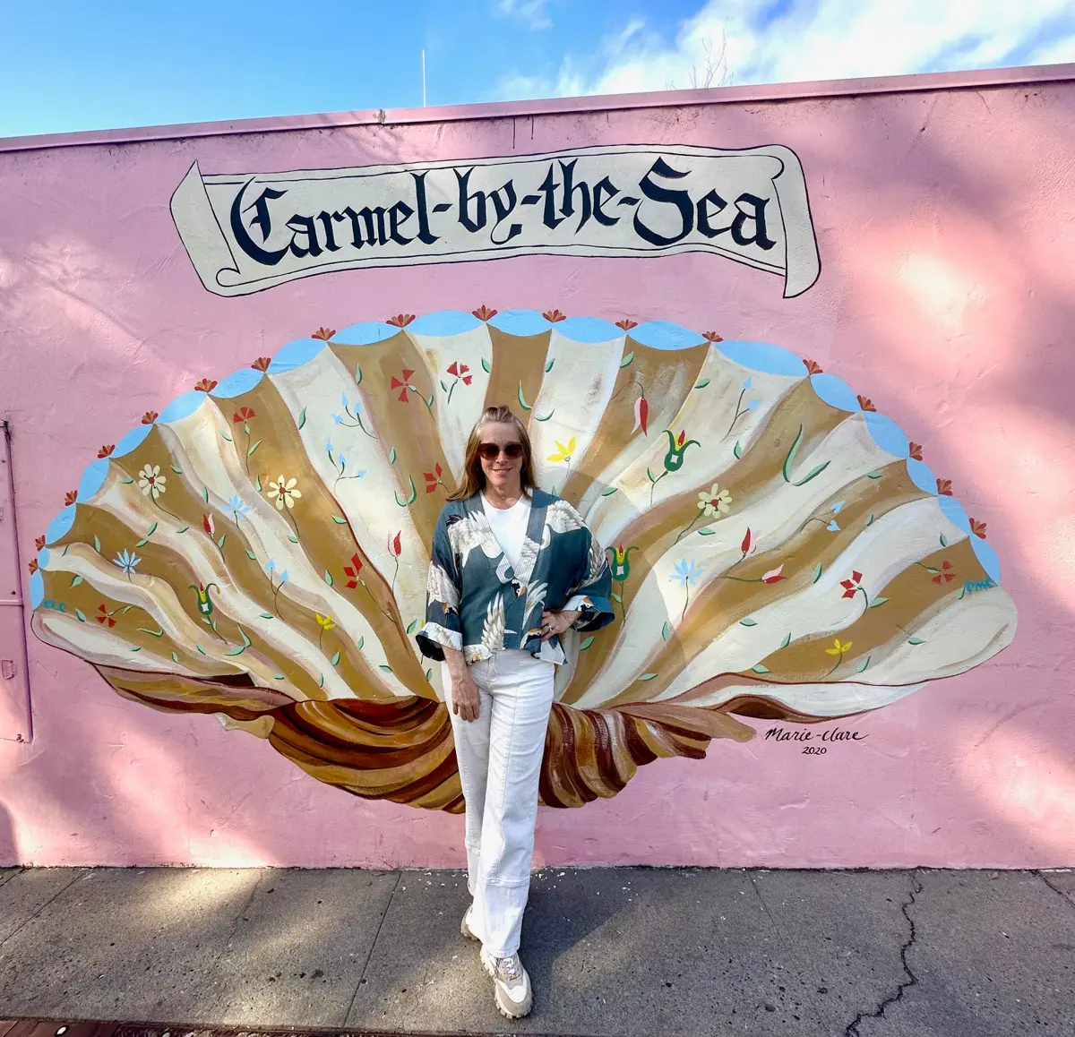 woman standing in front of carmel-by-the sea mural