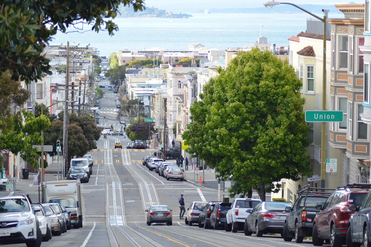 view of a san francisco street with cars and water in the background
