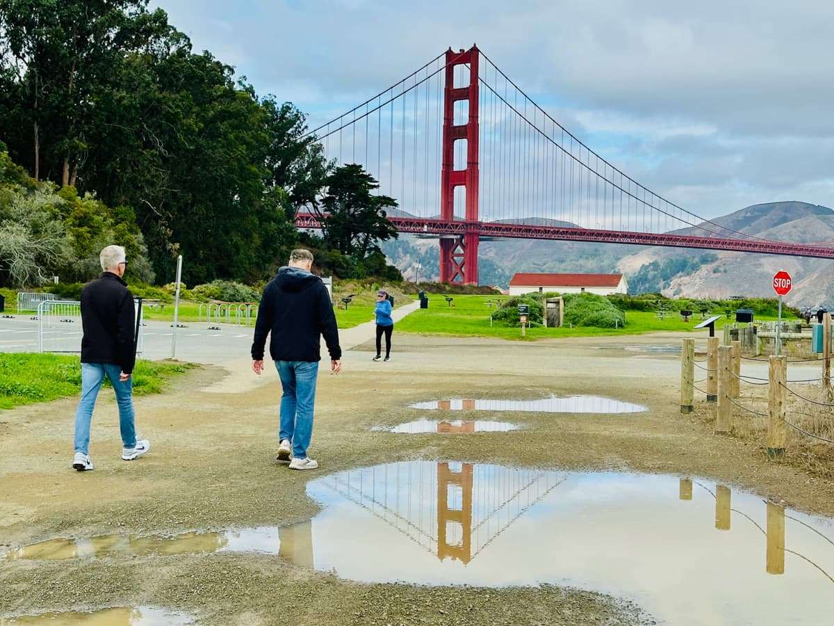 walking at crissy field with view of golden gate bridge and reflection in puddles after the rain
