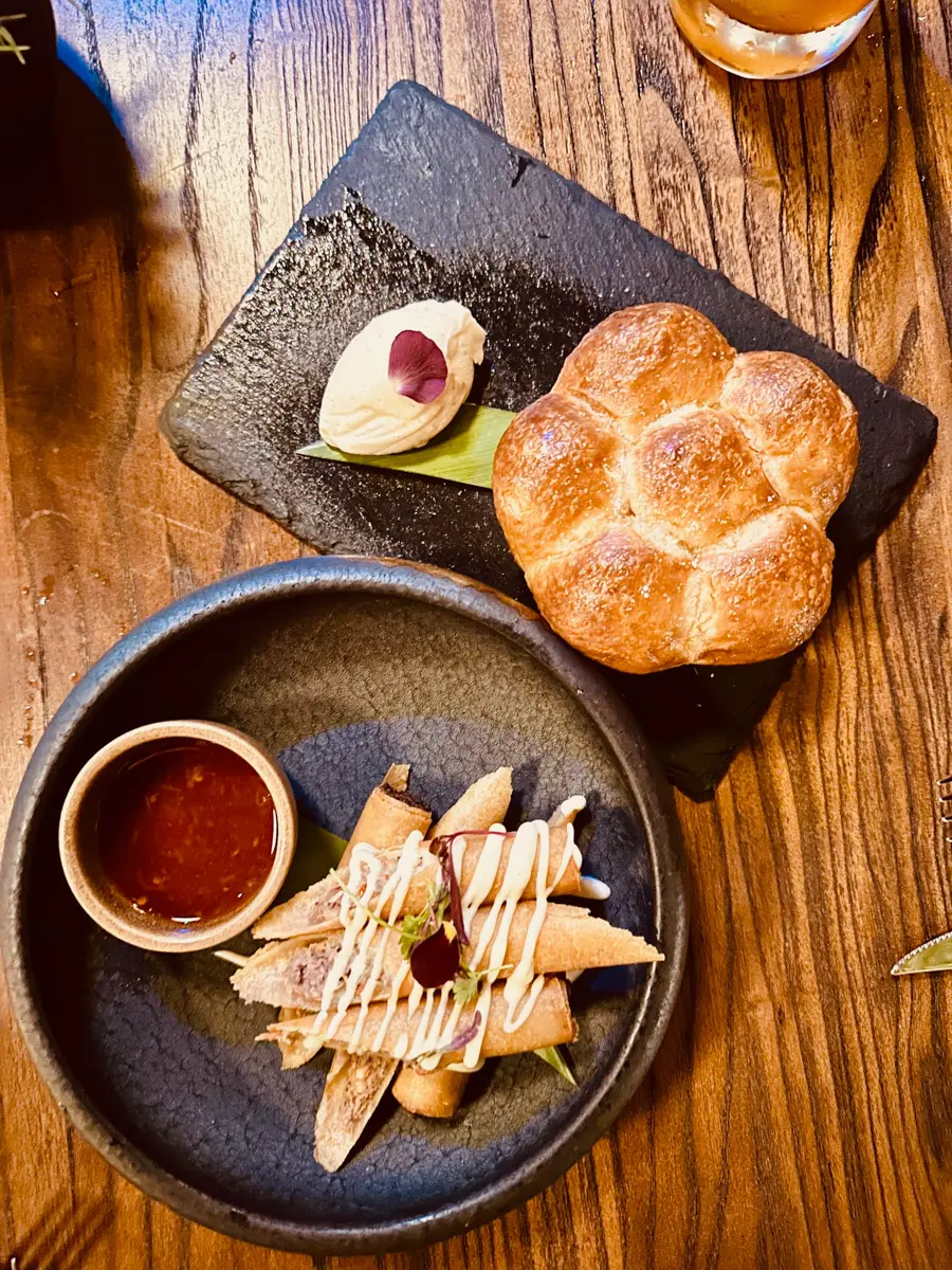 lumpia and milk bread on black plates at Hotel Zelos Dirty Habit in San Francisco