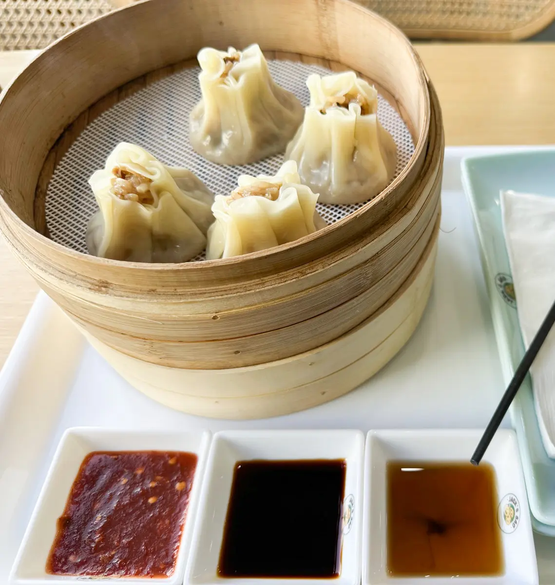 dumplings in a steamer basket at dumpling king clement street with three sauces