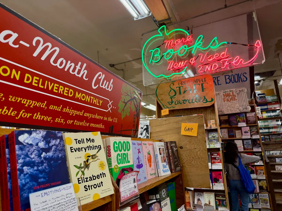 inside green apple books with shelves and neon sign
