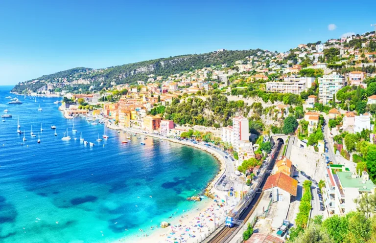 french riviera beach and bay with train tracks above the beach