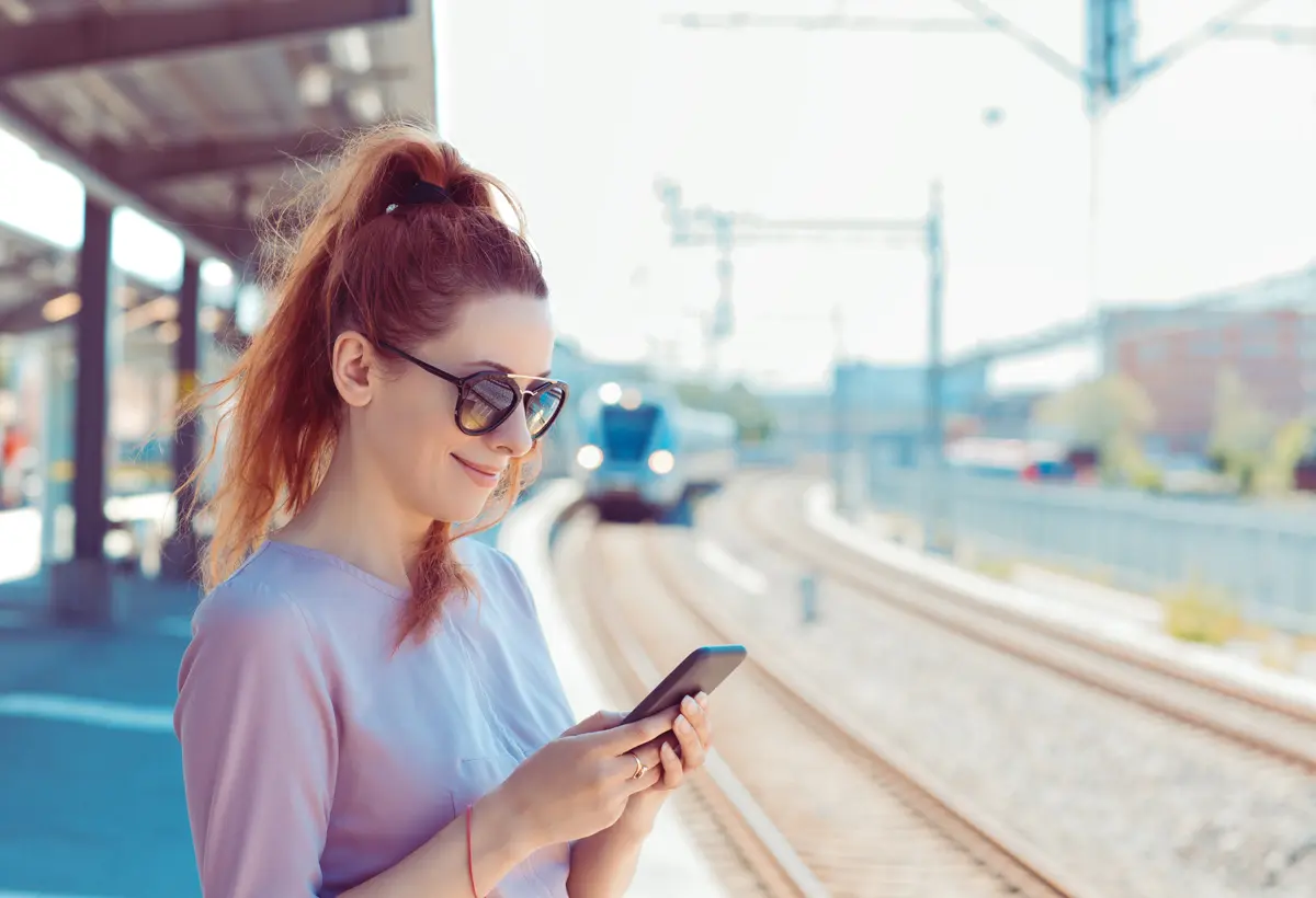 redhead using a phone at train station
